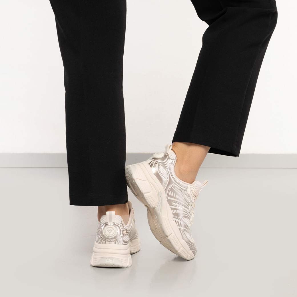Vista lateral do tênis casual Via Marte feminino dourado metalizado com detalhes brancos